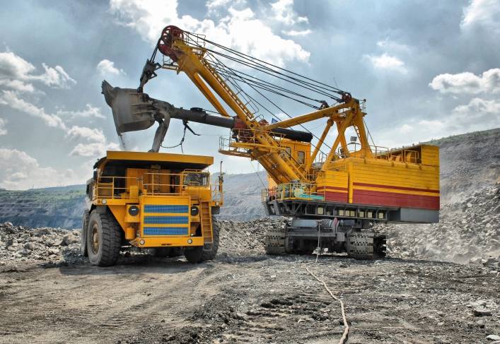 A large yellow truck is parked next to a dump truck.