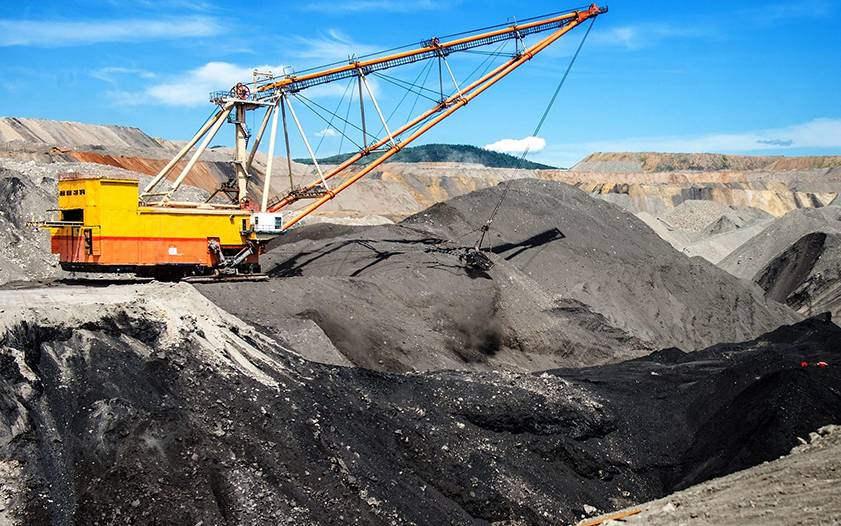 A large crane is in the middle of an open pit.